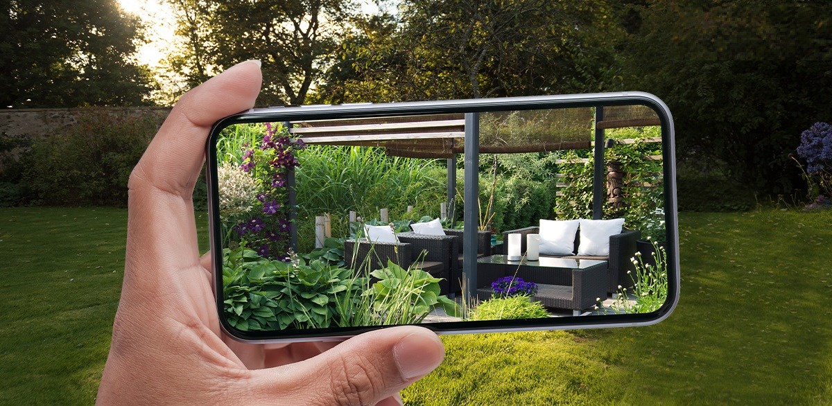 hand holding a phone taking picture of a garden with seating area
